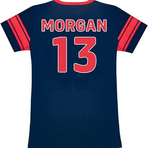 May include: Navy blue athletic jersey with red accents. The back of the jersey displays the name "MORGAN" in white block letters above the number "13" in red. Red stripes adorn the sleeves.