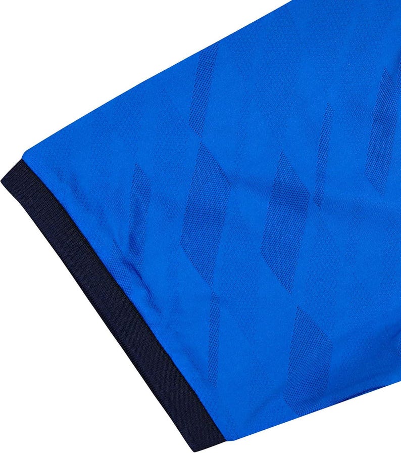 May include: Close-up of a blue athletic shirt with a textured pattern. The shirt has a dark blue collar and a diamond-shaped design. The fabric appears to be a breathable, moisture-wicking material.