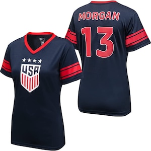May include: A navy blue soccer jersey with red and white accents. The jersey has the word "USA" and stars on the front and the number "13" and the name "MORGAN" on the back.
