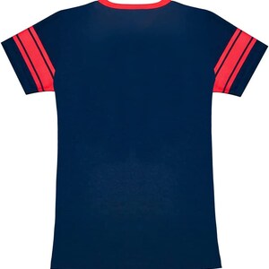 Puede incluir: Una camiseta azul marino con rayas rojas y blancas en las mangas.
