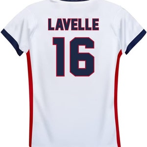 May include: White soccer jersey with red and blue trim. The back of the jersey has the name "LAVELLE" and the number "16" in navy blue with a red outline.