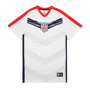 May include: White soccer jersey with red and navy blue accents. The jersey features a stylized brushstroke design and the word "USA" in a navy blue shield.