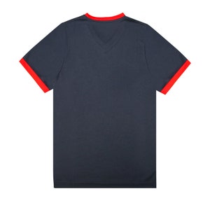 May include: A dark blue t-shirt with red trim around the neck and sleeves.