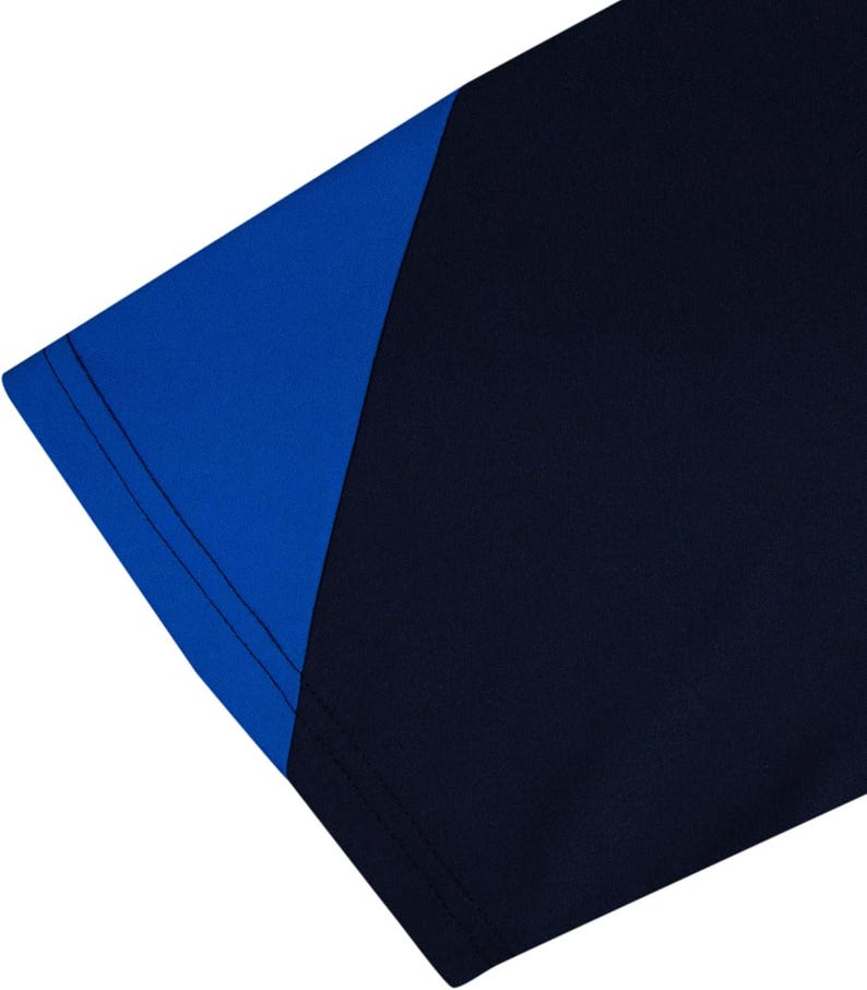 May include: Close-up of a navy blue and royal blue athletic shirt. The shirt features a color block design with a royal blue shoulder and sleeve panel. The seams are visible, and the fabric appears to be a smooth, athletic material.