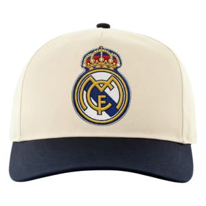 May include: Cream-colored baseball cap with a navy blue brim and a black button. The cap features an embroidered emblem with a crown and the letters "MCF" in gold, blue, and white. A stylish accessory for sports fans.