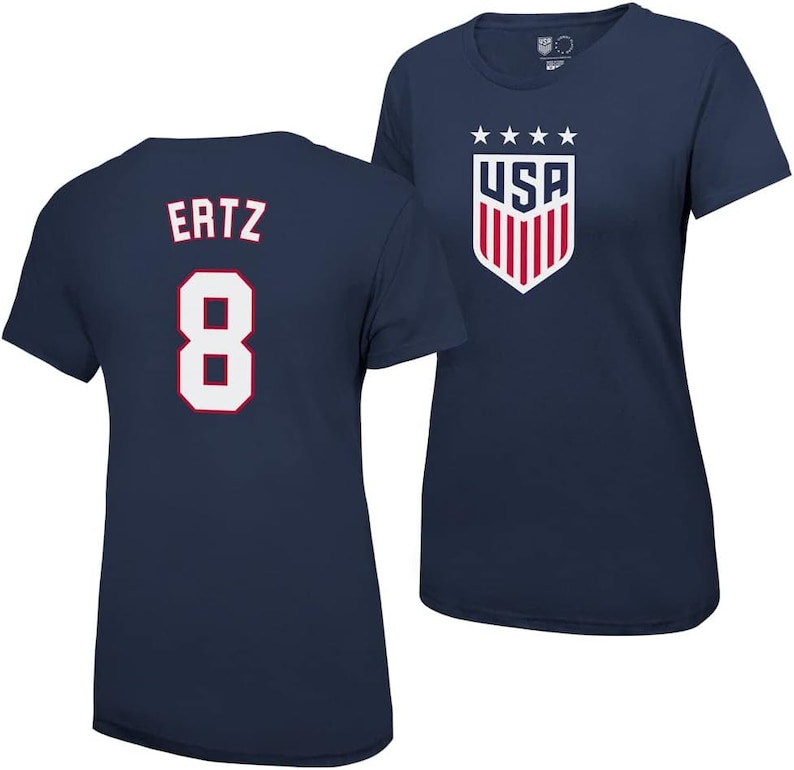 Puede incluir: Dos camisetas azul marino con letras blancas. Una camiseta tiene el n&uacute;mero "8" y el nombre "Ertz" en la espalda. La otra camiseta tiene un escudo de EE. UU. blanco y rojo con cinco estrellas arriba.