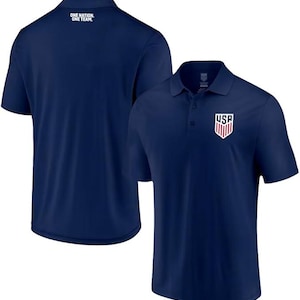 May include: Two navy blue polo shirts. One shirt has the text "ONE NATION, ONE TEAM" on the back. The other shirt has a red, white, and blue USA logo on the left chest.
