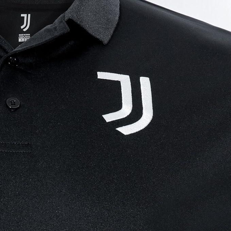 May include: Black polo shirt with a white "J" logo on the right side of the chest. The shirt has a button-up collar and a single button on the left side of the chest.