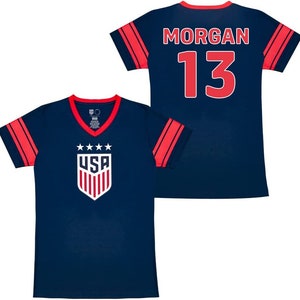 May include: Two navy blue soccer jerseys with red and white accents. One jersey has the text "USA" and a shield with stars. The other jersey has the text "MORGAN 13".