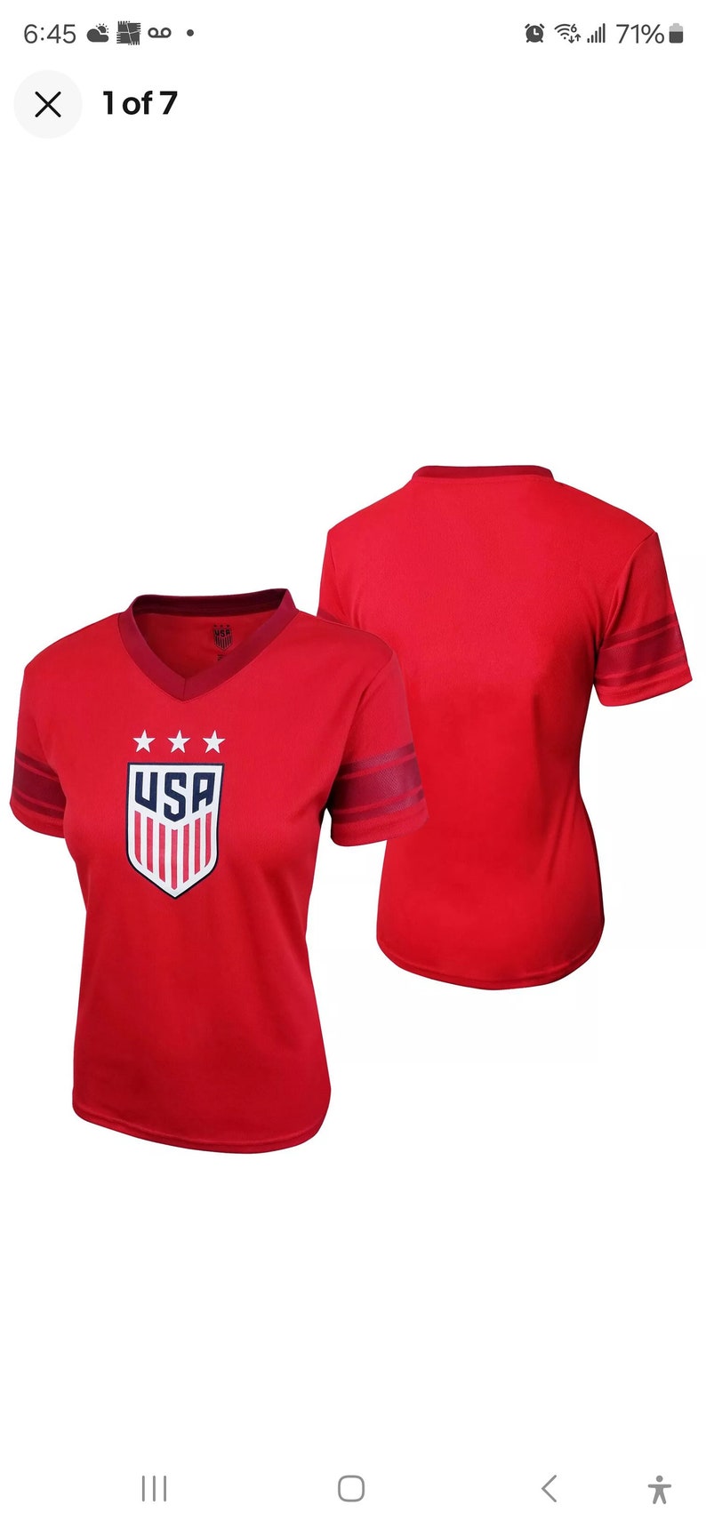 Puede incluir: Camiseta roja de manga corta con un logotipo de EE. UU. blanco y azul y rayas rojas y blancas en las mangas. La parte posterior de la camiseta es de color rojo liso.