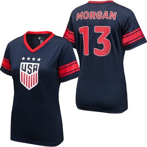 May include: A navy blue football shirt with red and white accents. The shirt has the word "USA" and three stars on the front, and the number "13" and the name "MORGAN" on the back.