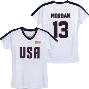 May include: White athletic jersey with navy blue accents. The front displays "USA" in navy lettering, a small American flag, and a V-neck collar. The back features "MORGAN" and the number "13" in navy.