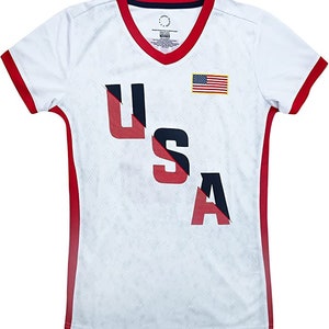 May include: White athletic jersey with red and blue trim. The jersey has a diagonal red and blue stripe with the word "USA" in red and blue letters. A small American flag is on the right side of the jersey.
