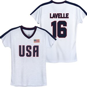 Puede incluir: Camiseta blanca con ribete azul marino y las palabras "USA" y una peque&ntilde;a bandera estadounidense en la parte delantera. La parte posterior de la camiseta tiene el nombre "Lavelle" y el n&uacute;mero "16" en azul marino.
