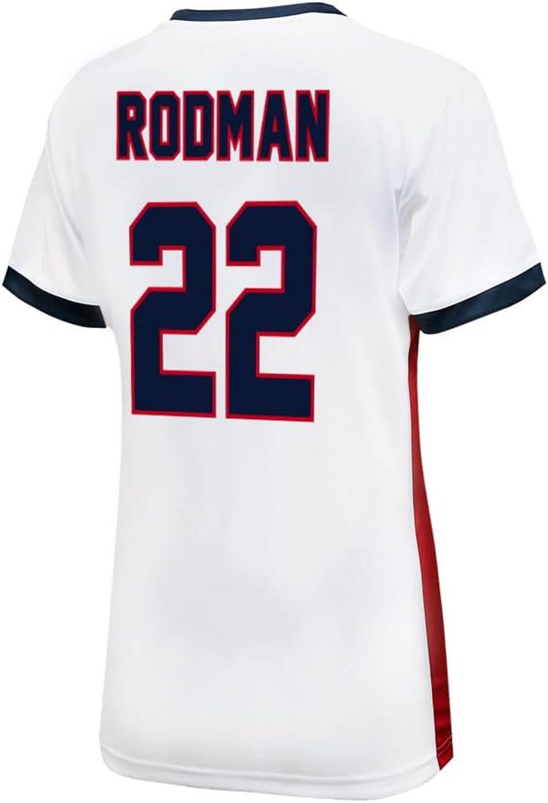 K&ouml;nnte beinhalten: Wei&szlig;es Trikot mit rotem und blauem Besatz. Auf der R&uuml;ckseite des Trikots steht der Name "RODMA" und die Nummer "22" in Blau mit roter Umrandung.
