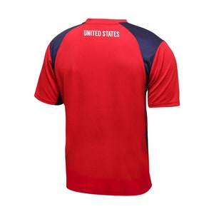 K&ouml;nnte beinhalten: Rotes und marineblaues Fu&szlig;balltrikot mit dem Text "UNITED STATES" auf der R&uuml;ckseite.