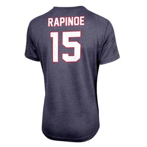 Pode incluir: Uma camiseta azul marinho com o nome "RAPINOE" e o n&uacute;mero "15" impressos nas costas em branco.