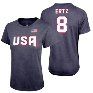 May include: A navy blue t-shirt with the word "USA" printed in white on the front and the name "ERTZ" and the number "8" printed in white on the back. The shirt has a distressed look and a small American flag on the front.