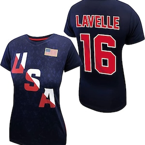 May include: A navy blue t-shirt with the word "USA" printed on the front in red, white, and blue. The back of the shirt has the name "LAVELLE" and the number "16" printed in red.