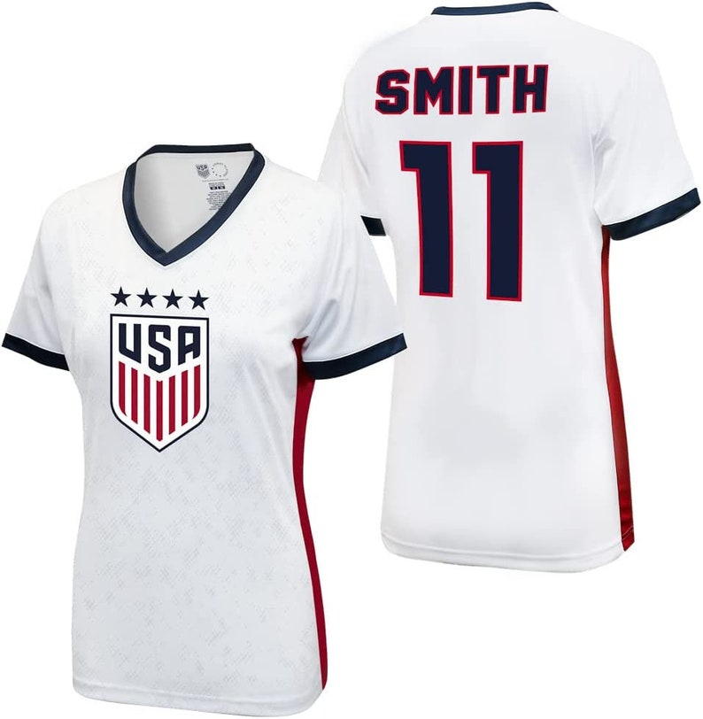 May include: White soccer jersey with red and blue trim. The jersey has the USA logo on the front and the name "SMITH" and the number "11" on the back.