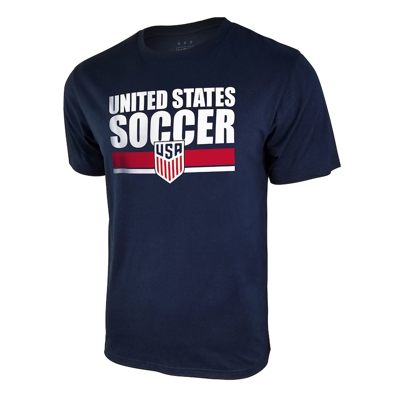 Pu&ograve; includere: Una maglietta blu navy con una grafica bianca che dice "UNITED STATES SOCCER" con uno scudo rosso, bianco e blu che dice "USA" sotto.