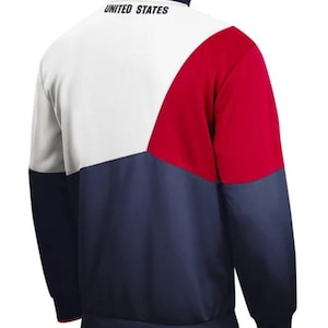 Puede incluir: Una chaqueta con cremallera blanca, roja y azul marino con las palabras "UNITED STATES" en la espalda.