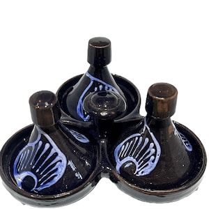 May include: A dark brown ceramic serving set featuring three connected bowls with conical lids. Each lid is decorated with a hand-painted light blue leaf-like pattern. The glossy finish covers the entire structure, which includes a central handle.