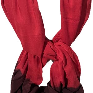 May include: A red and burgundy ombre scarf with a frayed edge.