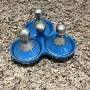 May include: A vintage blue ceramic condiment set with three sections. Each section has a silver-toned lid and a spiral design around the base. The set is designed to hold salt, pepper, and other spices.