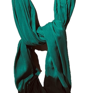 May include: A teal green scarf with a black ombre effect at the bottom. The scarf is made of a soft, flowing fabric and is folded in a loop.