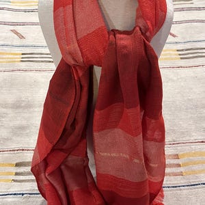 May include: A red and white striped scarf with a fringed edge. The scarf is made of a soft, lightweight fabric and is perfect for adding a touch of color to any outfit.