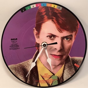 May include: A purple vinyl record clock featuring a close-up image of David Bowie. The record is titled "Move On" and is from the album "Fashion".