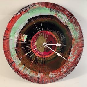 May include: A round wall clock made from a repurposed vinyl record. The clock face features concentric rings of red, green, and brown paint with white clock hands. The center of the clock has text that reads "FORUM RECORDS".