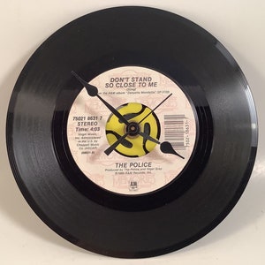 May include: A black vinyl record clock featuring The Police's "Don't Stand So Close to Me" single. The clock face is a yellow and black stylized symbol with black hands. The record label text reads "Don't Stand So Close to Me (Sting) from the A&M album "Zenyatta Mondatta" SP-3720). 75021 8631 7 STEREO Time: 4:03 Virgin Music, Inc. Administered in the U.S. by Chappell Music Co. (ASCAP) (08631-8) THE POLICE Produced by The Police and Nigel Gray © 1980 A&M Records, Inc.  AM RECORDS"