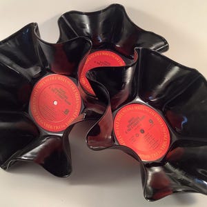May include: Three black vinyl records shaped into bowls with wavy, flared edges. Each bowl features a central red Columbia label with text reading Bruce Springsteen & The E Street Band, including track listings and the Columbia brand name.