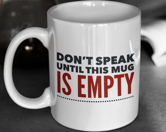 Könnte beinhalten: Weiße Keramiktasse mit schwarzem Text, der in Rot "Sprich nicht, bevor diese Tasse leer ist" lautet.