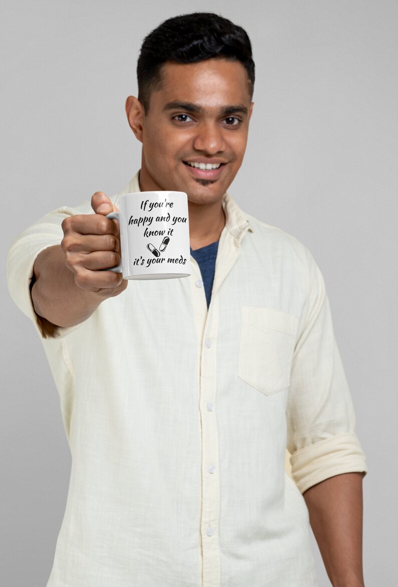 May include: White ceramic mug with black text that reads "If you're happy and you know it it's your meds" with a graphic of two pills.
