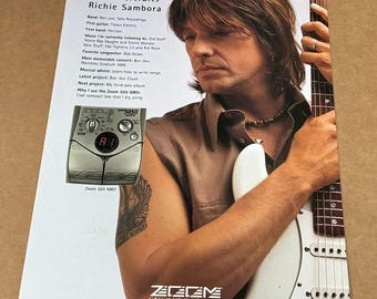 May include: A musician, Richie Sambora, is holding a white electric guitar. He is wearing a brown sleeveless shirt and a beaded necklace. He is holding a Zoom 505 MKII multi-effects pedal in his left hand. The text "Zoom Portraits" and "Catch Us If You Can" is visible in the image.