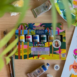Peut inclure: Un coffret de peintures gouache extra-fines avec le texte "LINEL GOUACHE EXTRA-FINES SELECTION VOYAGE". La boîte contient six tubes de peinture de 14 ml. Des tubes de peinture et des pinceaux sont également visibles.