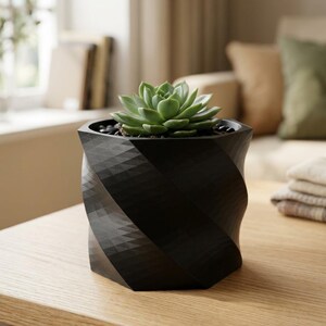 May include: A black planter with a geometric, spiraling, faceted surface texture. The planter contains a green succulent plant nestled among small black pebbles. The object has a hexagonal base and a wide, open top rim for the plant.