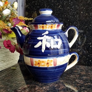 May include: Blue and white ceramic teapot with a matching cup. The teapot has a floral design and the word "和" written on it. The cup has a floral design and a handle.