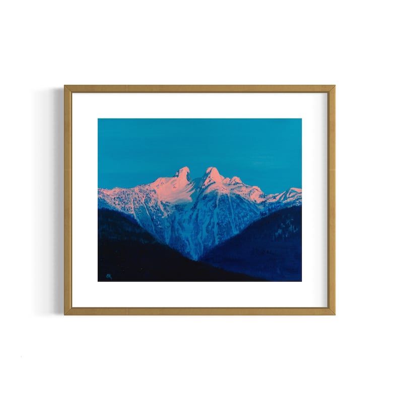 Op de afbeelding: Een ingelijste foto van een bergketen met besneeuwde toppen. De lucht is een levendig blauw en de bergen zijn diepblauw met roze accenten.
