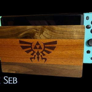 May include: A wooden stand with a Triforce design, made of different wood types, holding a teal Nintendo Switch console.