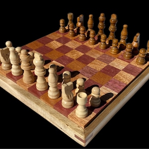 May include: A wooden chess set with light and dark brown pieces on a purple and brown checkerboard. The board is made of wood and has a natural finish.