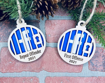 Könnte beinhalten: Zwei hölzerne Weihnachtskugeln in Form einer Kugel mit einem blauen und weißen Facebook-Logo im Inneren. Die Kugeln sind mit dem Text "Repeat Offender 2021" und "First Offense 2021" verziert.