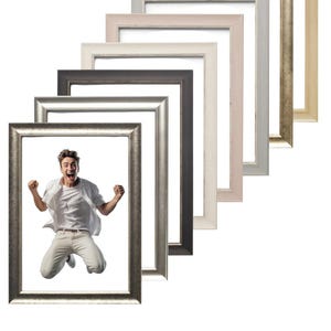 May include: A collection of rectangular picture frames in various colors, including silver, black, white, and beige. One frame contains a person jumping in the air. The frames are arranged in a diagonal line.