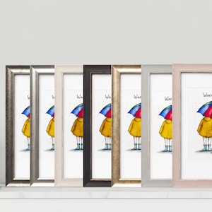Könnte beinhalten: Eine Reihe von sieben gerahmten Kunstdrucken mit einer farbenfrohen Illustration von zwei Figuren und einem kleinen Hund unter einem Regenbogen-Regenschirm mit dem Text "Warm Inside". Die Rahmen haben verschiedene metallische und neutrale Oberflächen.