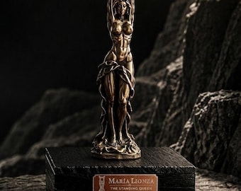 May include: A bronze-colored sculpture of a standing figure with arms raised above the head, mounted on a black rectangular base. A copper-colored plaque on the base reads: MARÍA LIONZA, THE STANDING QUEEN, SOLID BRONZE, UNIQUE SCULPTURE, HANDMADE.