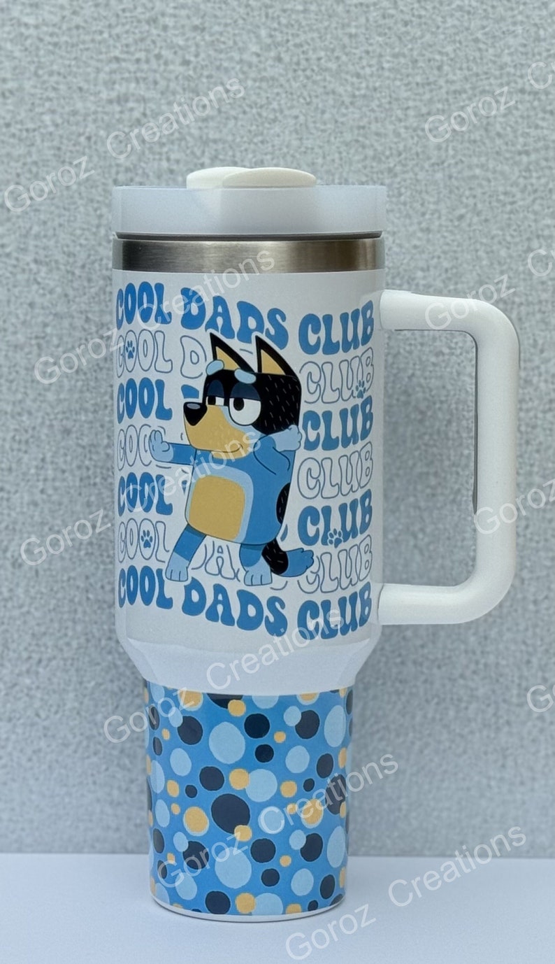 May include: White travel mug with a blue and yellow cartoon dog and the text "Cool Dads Club" repeated multiple times. The bottom of the mug has a blue, black, and yellow polka dot pattern.
