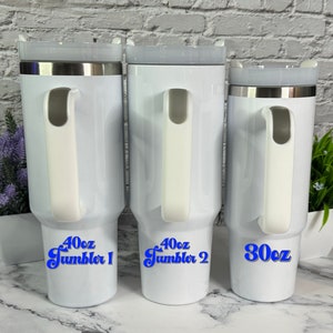 May include: Three white stainless steel travel mugs with blue text. The mugs are 40 oz, 40 oz, and 30 oz. The mugs have a handle and a lid.